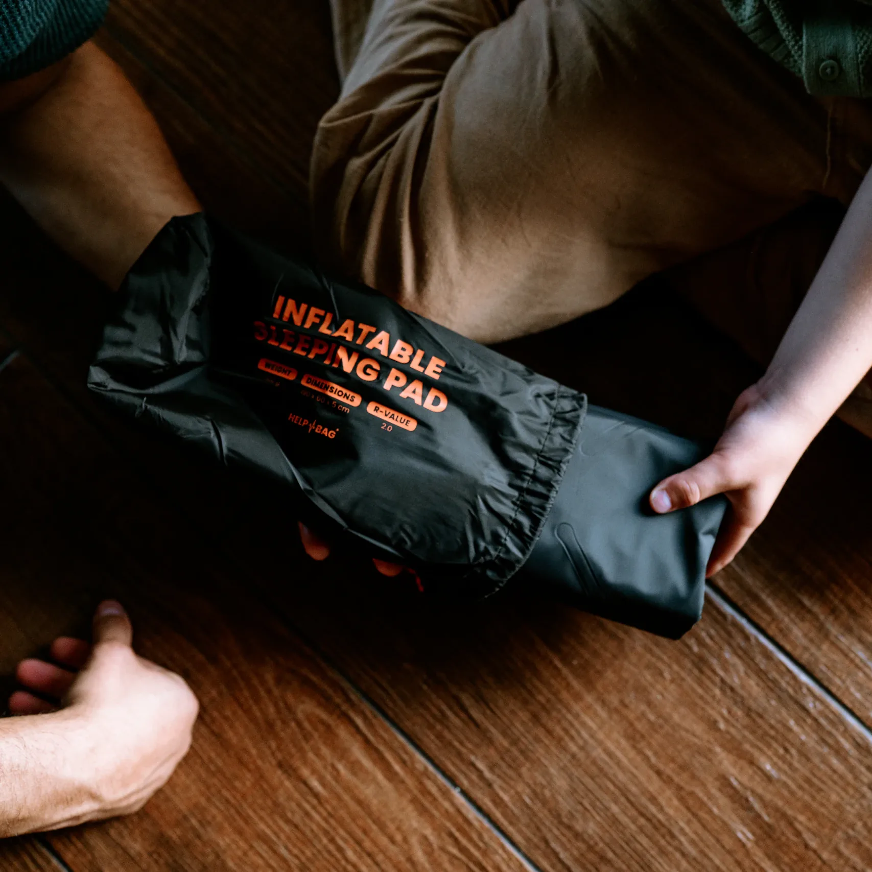 Zwinięta dmuchana mata do spania HELP BAG zsuwana z pokrowca z napisem INFLATABLE SLEEPING PAD