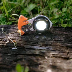 Włączona lampa LED COB młotka ratunkowego HELP BAG na drewnianej belce w trawie
