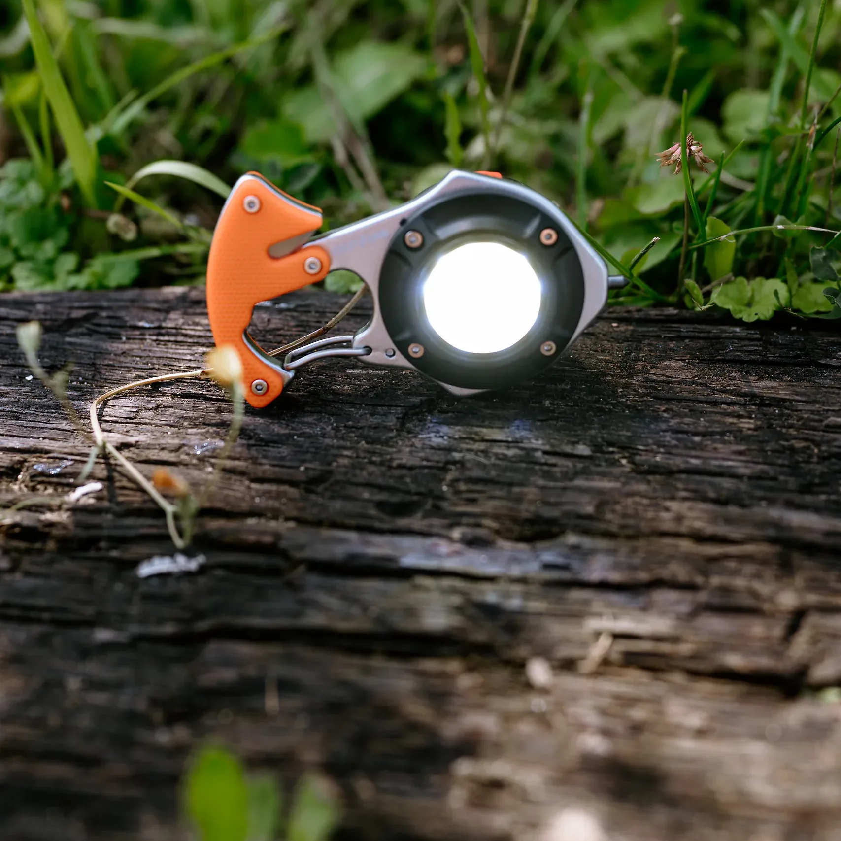 Włączona lampa LED COB młotka ratunkowego HELP BAG na drewnianej belce w trawie