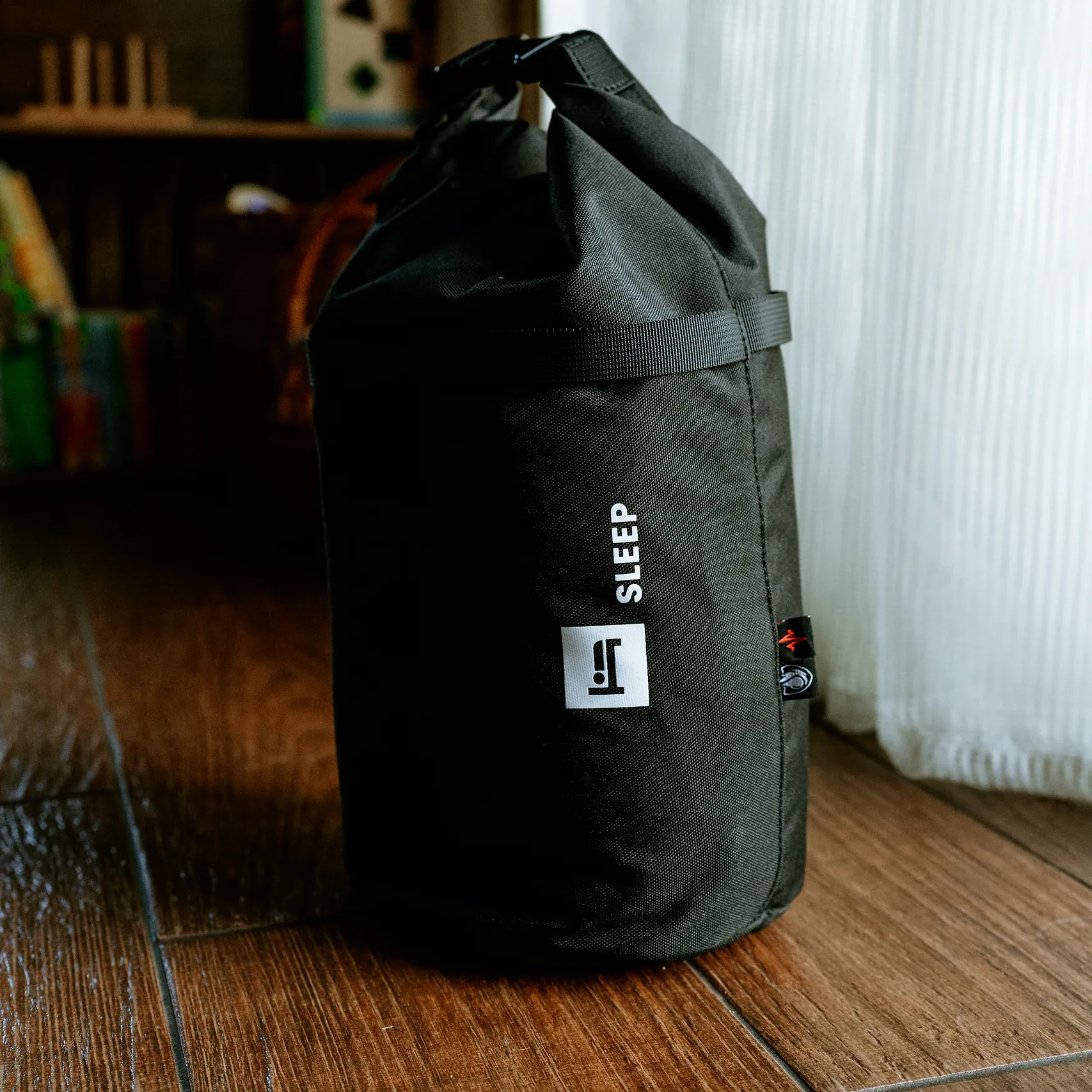 Moduł SLEEP HELP BAG w formie czarnego worka zwijanego od góry, stojący na drewnianej podłodze