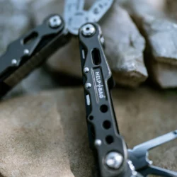 Rękojeść multitoola HELP BAG z logo i otworami zmniejszającymi wagę, w tle kombinerki