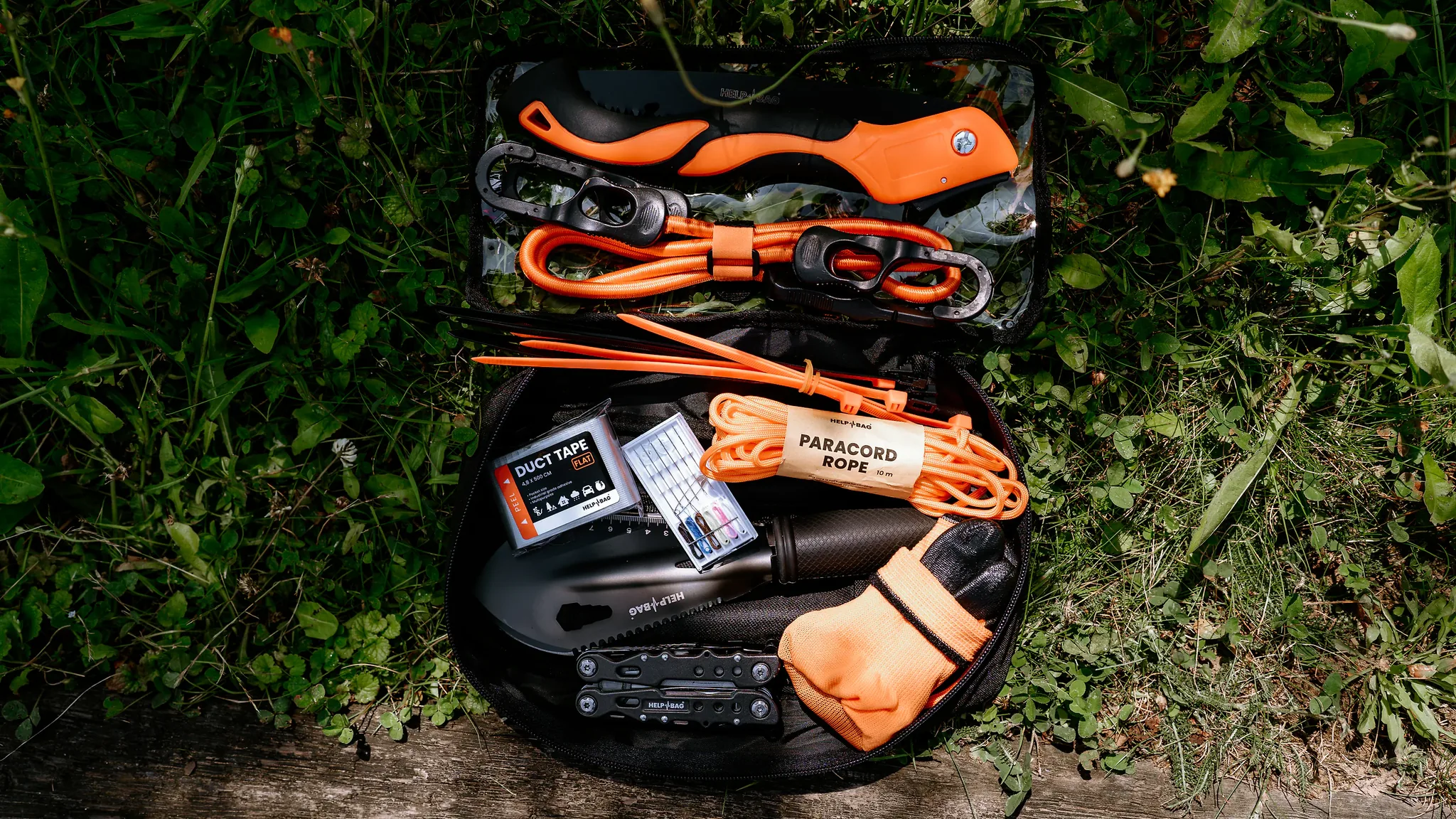 Otwarty moduł TOOLS z zestawu MAX PRO na trawie: linki elastyczne HELP BAG, piła, paracord, taśma