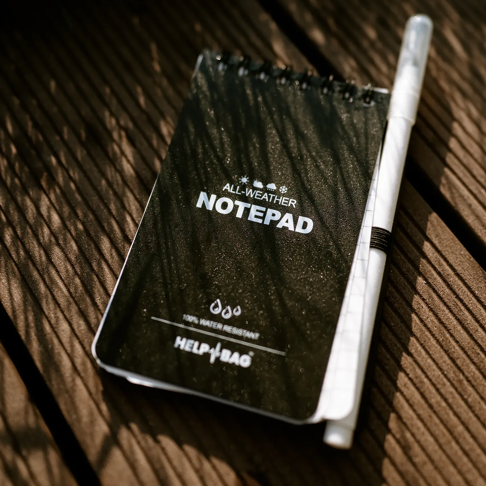 Notes wodoodporny HELP BAG z ołówkiem w gumce na tarasie, napis 100% WATER RESISTANT