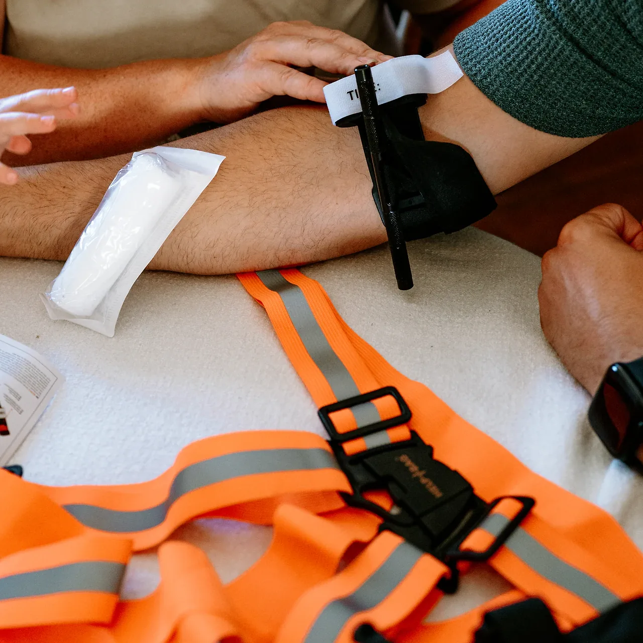 Opaska uciskowa HELP BAG na ręce: czarny pręt skręcający i biały pasek z napisem TIME