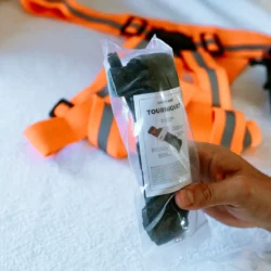 Opaska uciskowa HELP BAG w fabrycznym woreczku z etykietą TOURNIQUET, w tle szelki