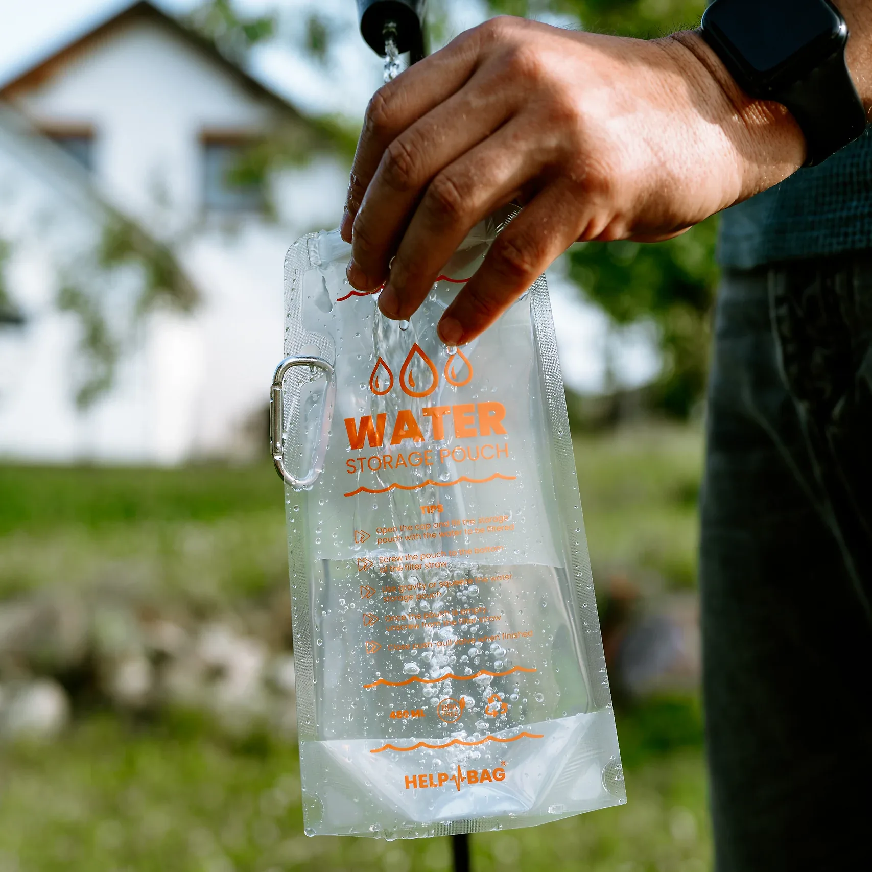 Napełnianie składanego pojemnika na wodę HELP BAG strumieniem wody z węża w ogrodzie