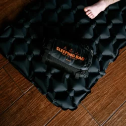Śpiwór HELP BAG w worku SLEEPING BAG położony na napompowanej dmuchanej macie