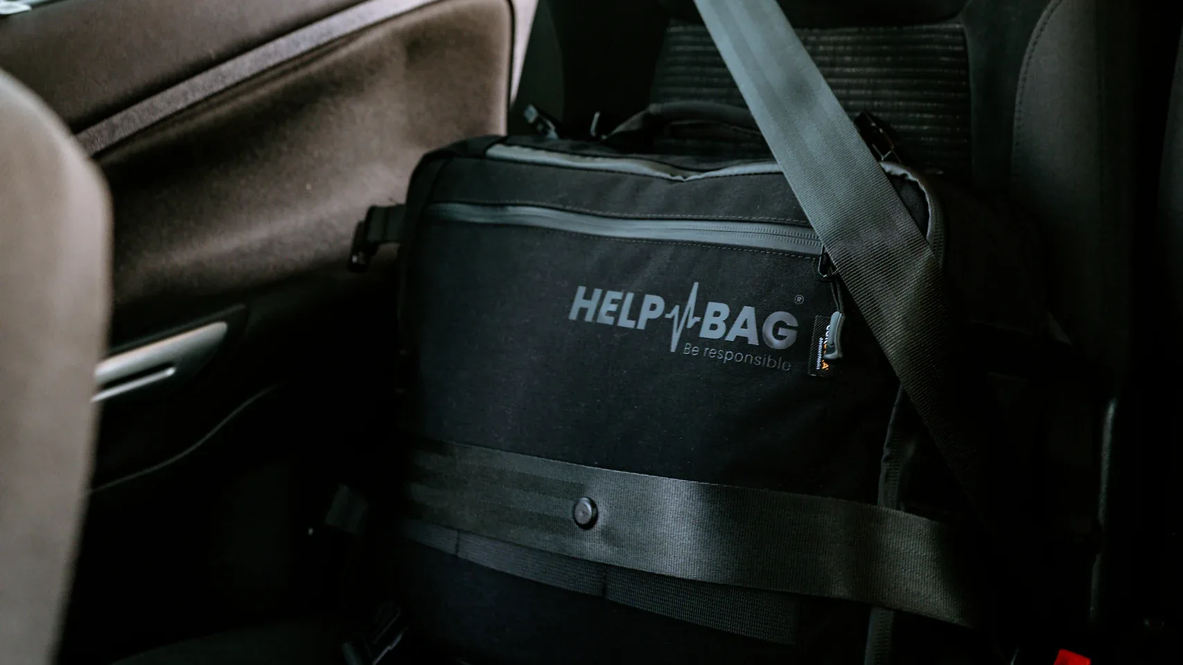 Czarna torba awaryjna HELP BAG przypięta pasem bezpieczeństwa na tylnej kanapie samochodu