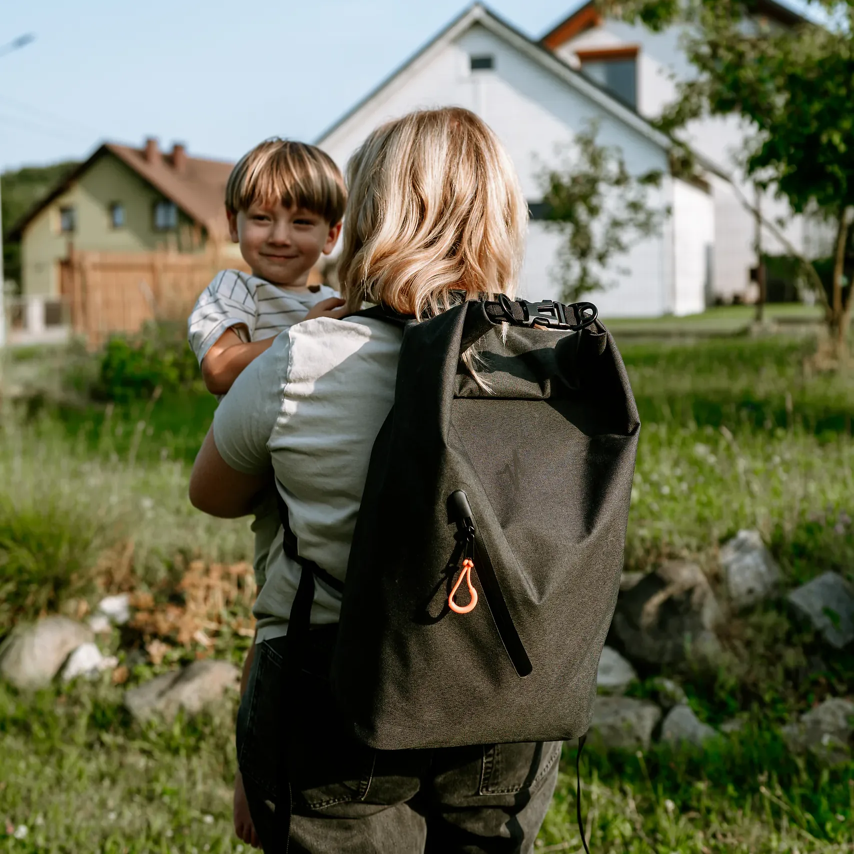 Mama niesie dziecko na ręku, na plecach ma zestaw awaryjny HELP BAG BASIC w wodoodpornym plecaku