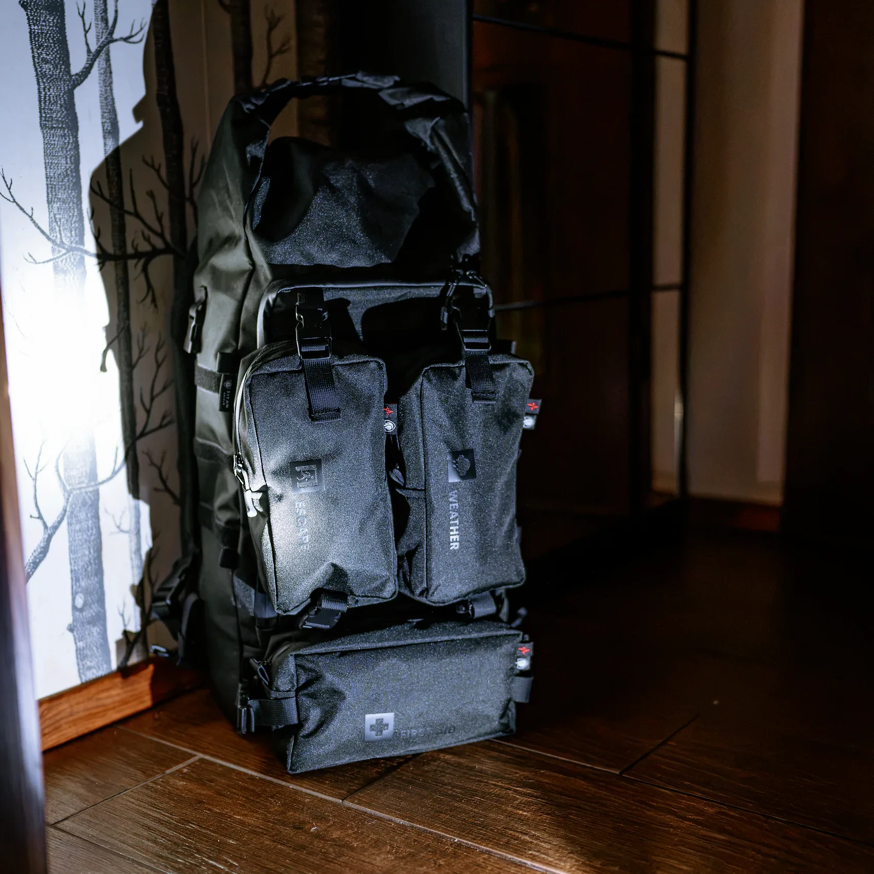 Spakowany plecak HELP BAG MAX PRO z modułami ESCAPE, WEATHER i FIRST AID w ciemnym przedpokoju