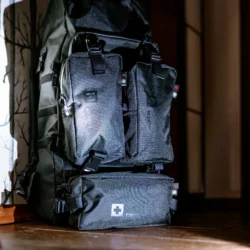 Plecak HELP BAG MAX PRO z modułami ESCAPE, WEATHER i FIRST AID z przodu, stojący w przedpokoju