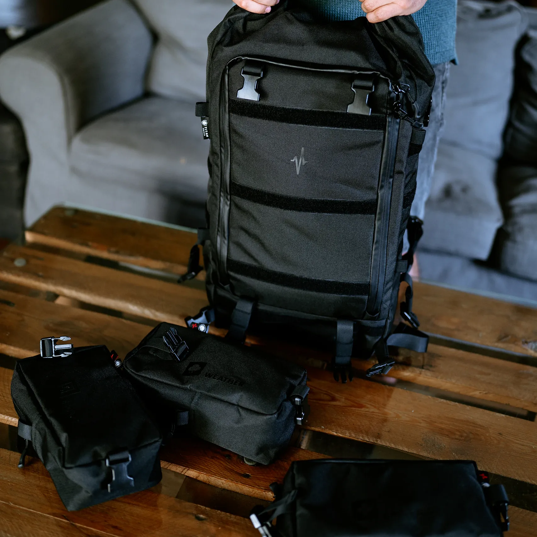 Plecak HELP BAG MAX PRO uniesiony nad stołem, obok odpięte moduły z klamrami